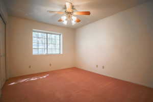 Carpeted spare room featuring a ceiling fan and baseboards