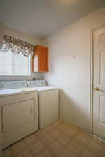 Laundry room featuring light floors, cabinet space, and washer and clothes dryer