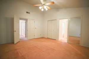 Unfurnished bedroom featuring light colored carpet, a closet, vaulted ceiling, and ceiling fan