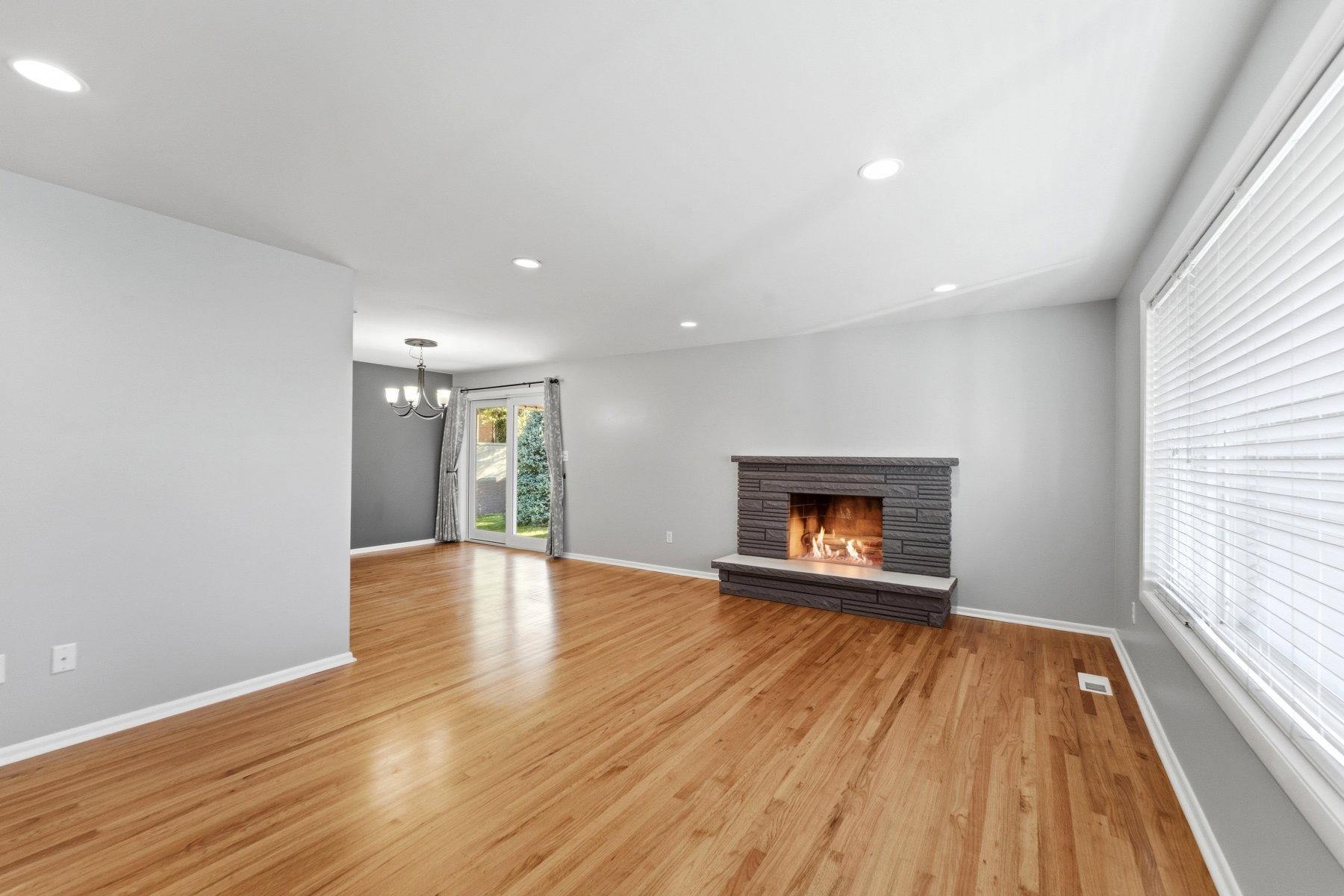 Unfurnished living room with light wood-style flooring, a chandelier, and a stone fireplace