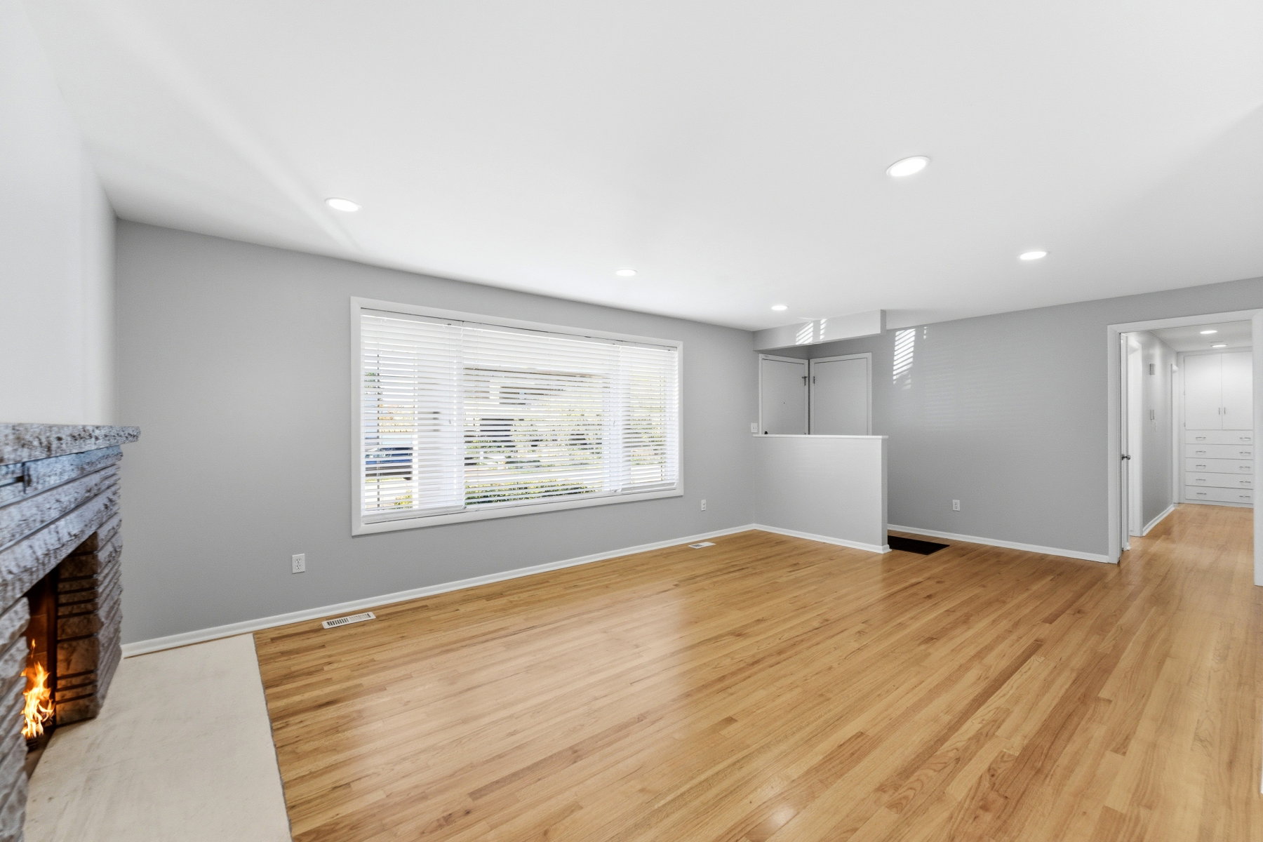 Unfurnished living room with light wood-style floors, a stone fireplace, and recessed lighting