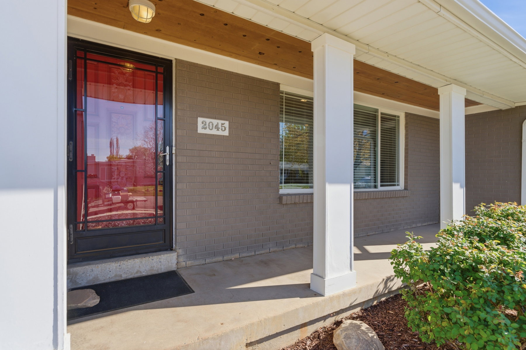 Doorway to property featuring a porch and brick siding