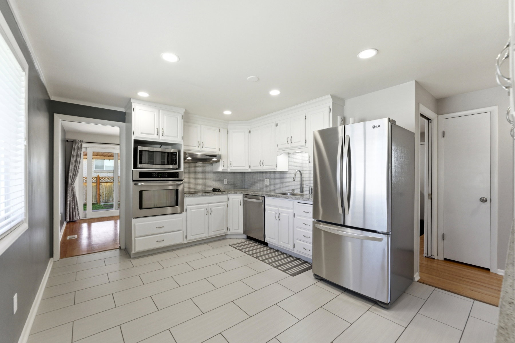 Kitchen featuring stainless steel appliances, white cabinets, decorative backsplash, and recessed lighting