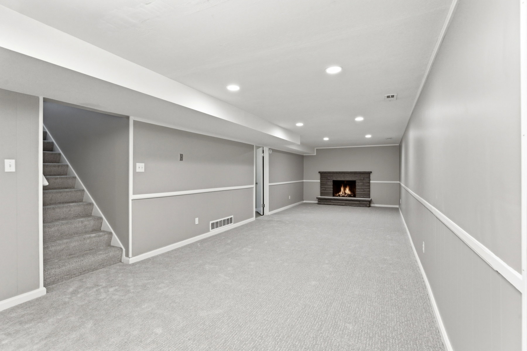 Finished below grade area with light colored carpet, a brick fireplace, and recessed lighting