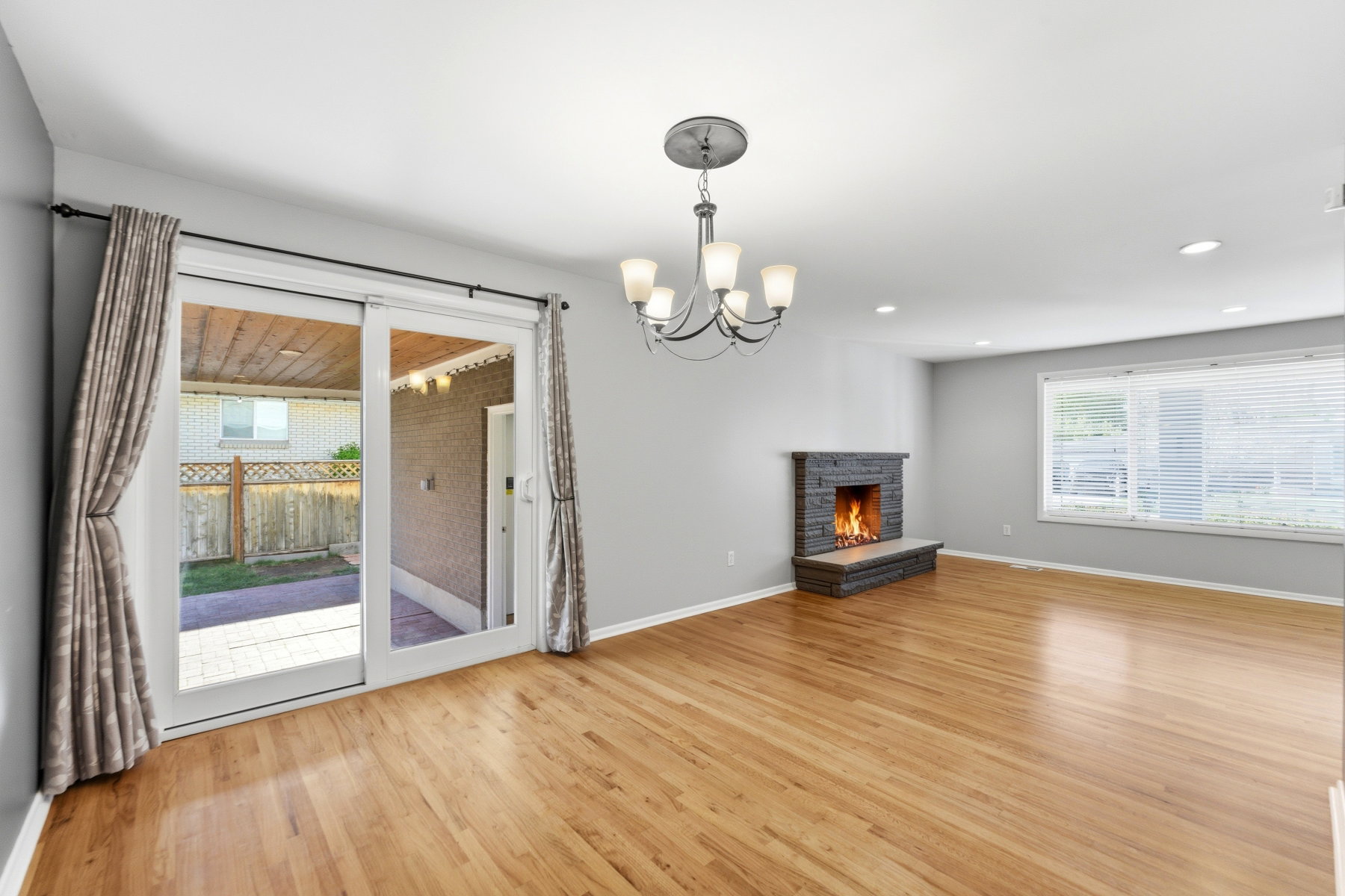 Unfurnished living room featuring suspended lighting, a stone fireplace, and light wood-type flooring