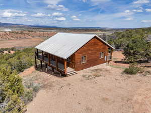 View of property exterior with a porch, a mountain view, faux log siding, a metal roof, and view of desert
