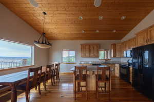 Kitchen featuring black appliances, a vaulted wood ceiling, a center island, a breakfast bar area, and dark wood-type flooring