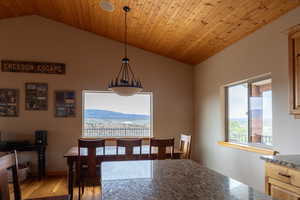 Dining space with light wood-style floors, a vaulted wooden ceiling, and a mountain view