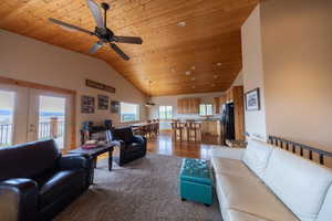 Living area featuring a vaulted wood ceiling, a ceiling fan, and dark colored carpet
