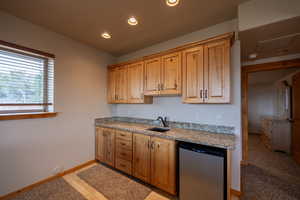 Kitchen with recessed lighting, light stone countertops, and wood finish cabinets