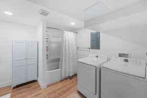 Laundry area with light wood-style flooring, electric panel, separate washer and dryer, and recessed lighting