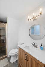 Bathroom featuring vanity, a stall shower, and dark tile patterned floors