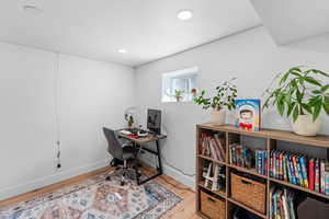 Home office with light wood-style floors and recessed lighting