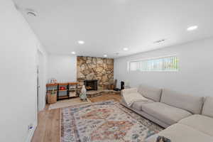 Living room with light wood finished floors, a fireplace, and recessed lighting