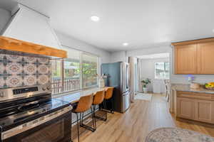 Kitchen with stainless steel appliances, light stone counters, light wood finished floors, recessed lighting, and light wood finish cabinetry