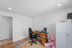 Home office with light wood finished floors and recessed lighting