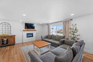 Living area with a glass covered fireplace, light wood finished floors, and recessed lighting