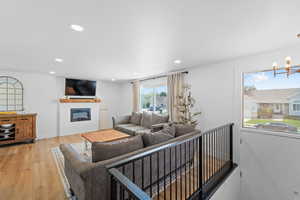 Living room with a glass covered fireplace, light wood finished floors, and a chandelier