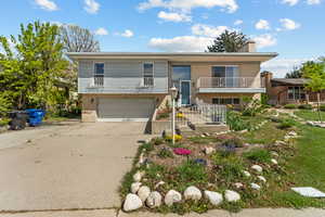 Split foyer home with a balcony, brick siding, an attached garage, and concrete driveway