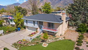 View of front of home featuring a mountain view, an attached garage, a chimney, brick siding, and driveway