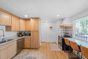 Kitchen featuring stainless steel appliances, light stone counters, light wood-style flooring, light wood finish cabinets, and recessed lighting