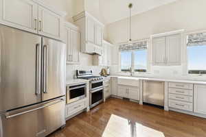 Kitchen featuring high quality appliances, light wood finished floors, white cabinets, and lofted ceiling