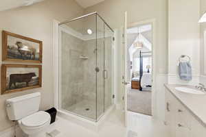 Ensuite bathroom featuring light tile patterned floors, vanity, a shower stall, vaulted ceiling, and light colored carpet