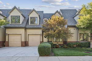 View of front of house with an attached garage, driveway, a shingled roof, and stucco siding