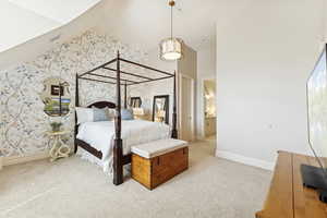 Bedroom with light colored carpet, a high ceiling, connected bathroom, and wallpapered walls