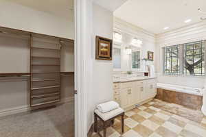 Bathroom with a walk in closet, double vanity, and a garden tub