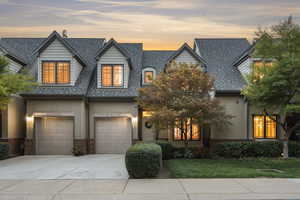 View of front of home featuring a garage, stucco siding, concrete driveway, and brick siding