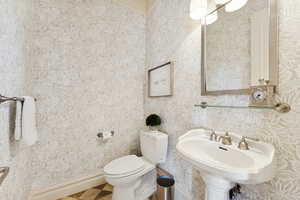 Half bathroom featuring wallpapered walls