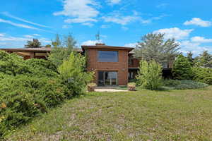 Back of house featuring brick siding, a yard, and a patio area