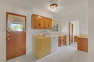Laundry room featuring cabinet space, light flooring, washing machine and dryer, and a textured ceiling