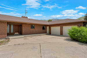 View of front of house with a garage, driveway, brick siding, and roof with shingles