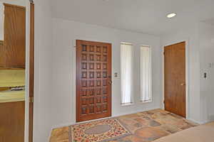 Foyer entrance with stone finish flooring and recessed lighting