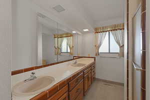 Full bath with double vanity, plenty of natural light, and a stall shower
