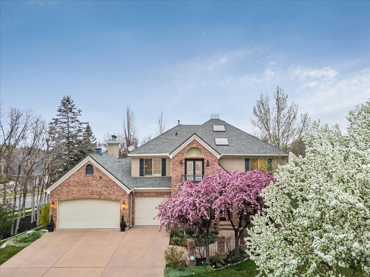 Traditional-style residence featuring a brick and stucco exterior, a gray shingled roof, and a two-car garage