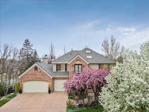 Traditional-style residence featuring a brick and stucco exterior, a gray shingled roof, and a two-car garage