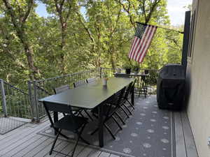 Spacious exterior deck with composite flooring and metal railings, surrounded by mature trees