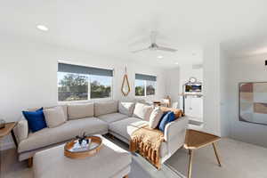 Carpeted living room with ceiling fan and recessed lighting