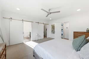 Bedroom featuring a barn door, light carpet, crown molding, a ceiling fan, and ensuite bath