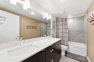 Bathroom featuring double vanity, shower / tub combo, and light tile patterned flooring