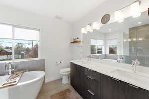 Full bathroom featuring a soaking tub, double vanity, a shower stall, and light tile patterned floors