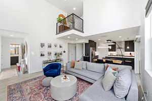 Living room with a high ceiling, light wood-type flooring, and recessed lighting