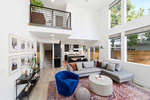 Living room with light wood-style floors, recessed lighting, and a high ceiling