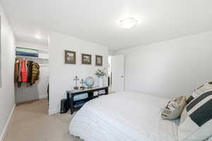 Bedroom featuring a spacious closet and light colored carpet