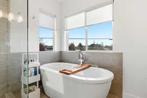 Full bathroom with tile walls and a freestanding bath