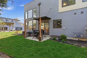 Rear view of house with a patio area, stucco siding, and a yard