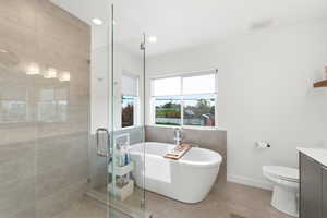 Bathroom featuring vanity, a stall shower, a freestanding bath, light tile patterned flooring, and recessed lighting